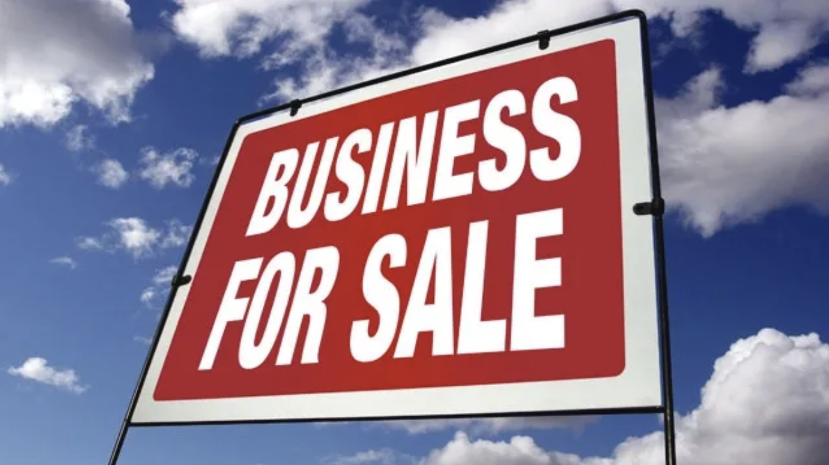 A large red and white sign stating ‘Business For Sale’ with a blue sky in the background.