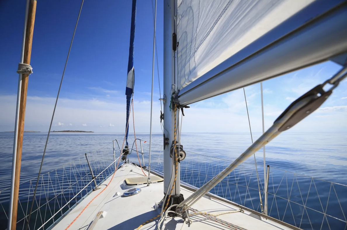 The Bow of a sailboat setting out in the wide open ocean.