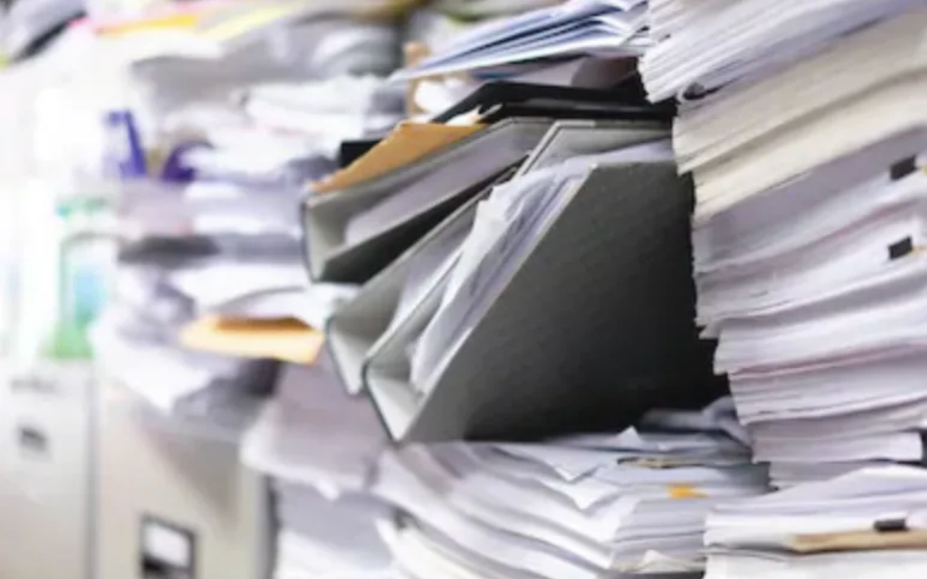 A close-up view of disorganized binders sitting on top of a pile of scattered paper.