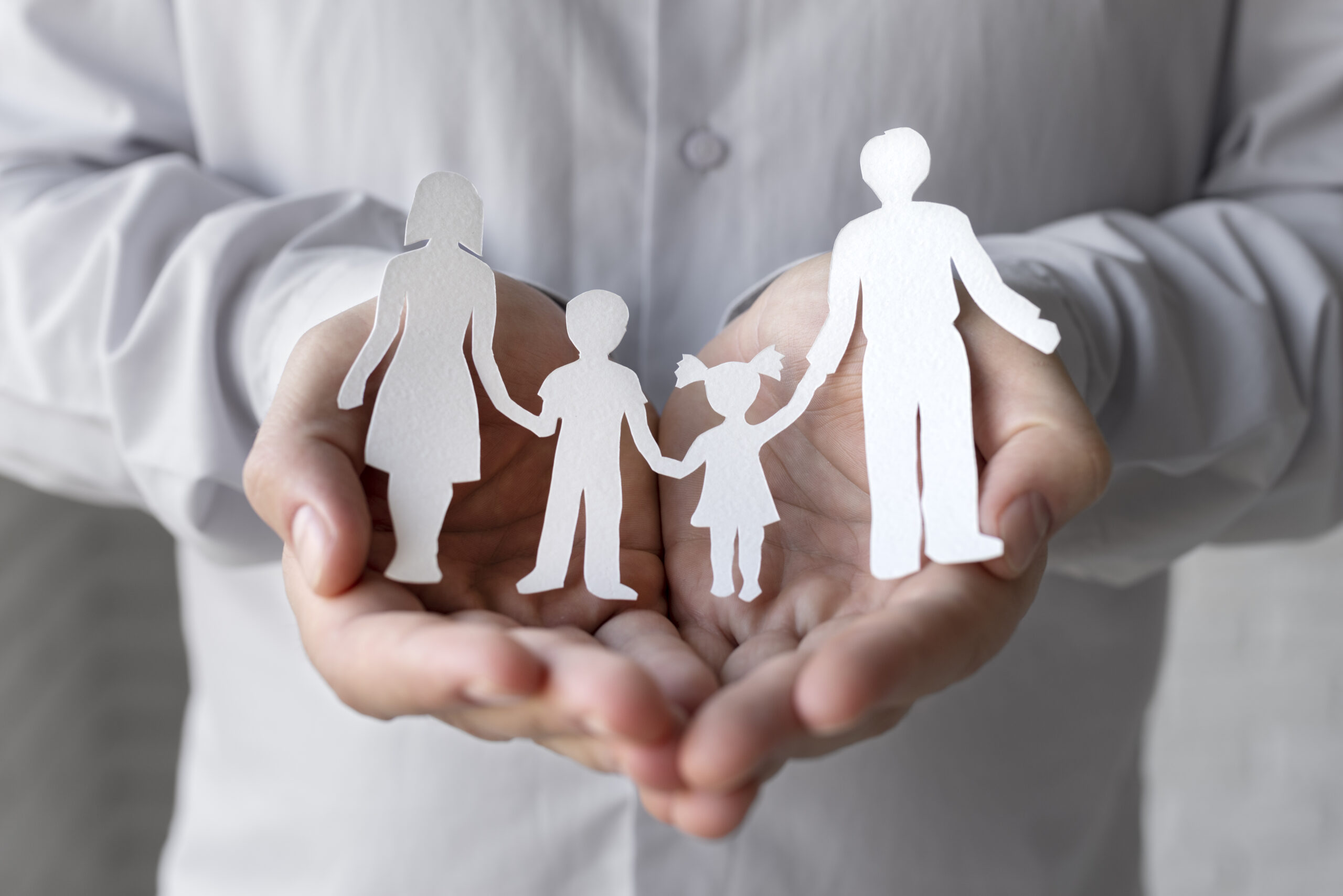 Hands holding paper people close up symbolizing a family trust