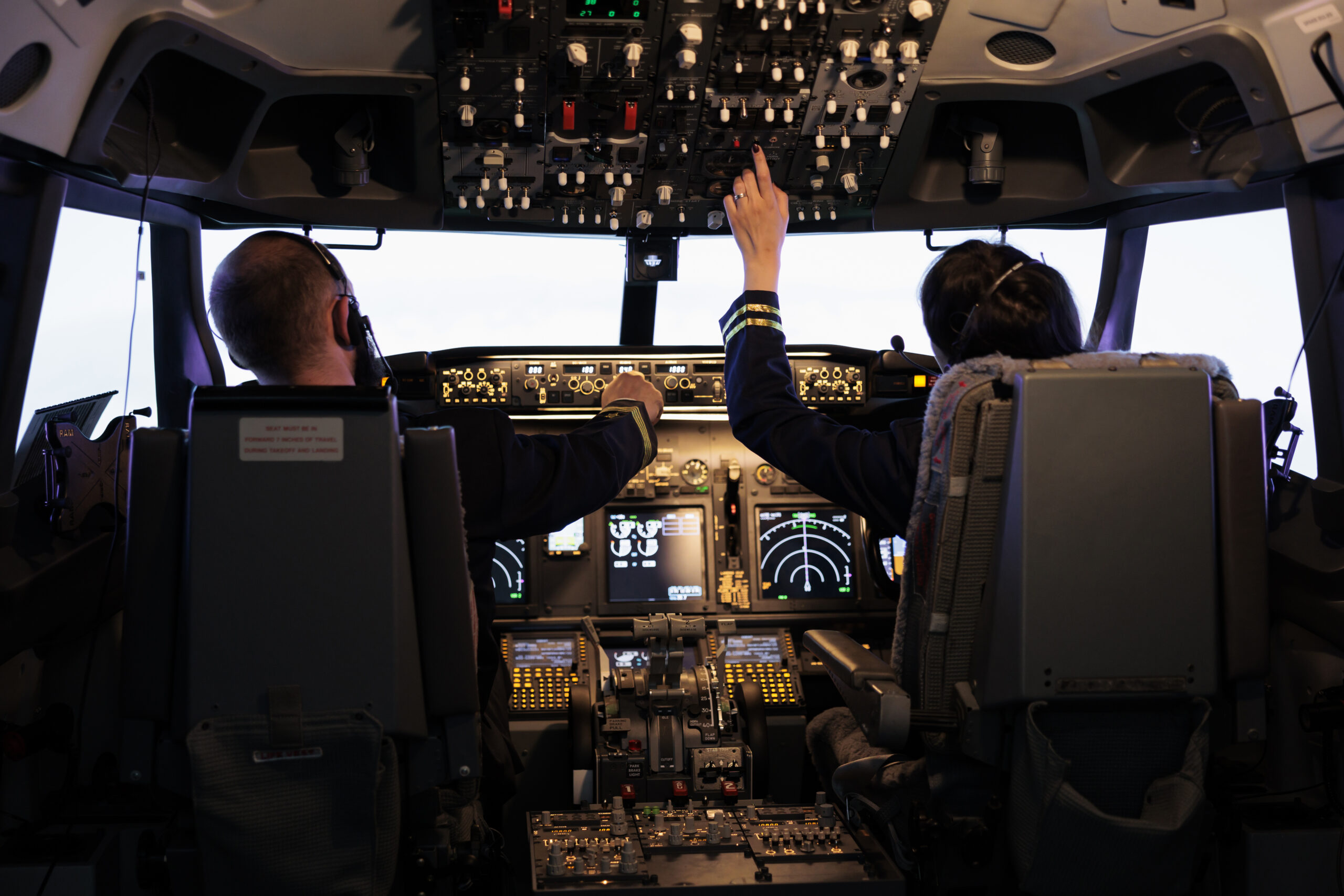 Captain and woman copilot getting ready to fly airplane and takeoff with dashboard navigation in cockpit command. Airline crew fixing altitude level and with control panel buttons, flying plane.